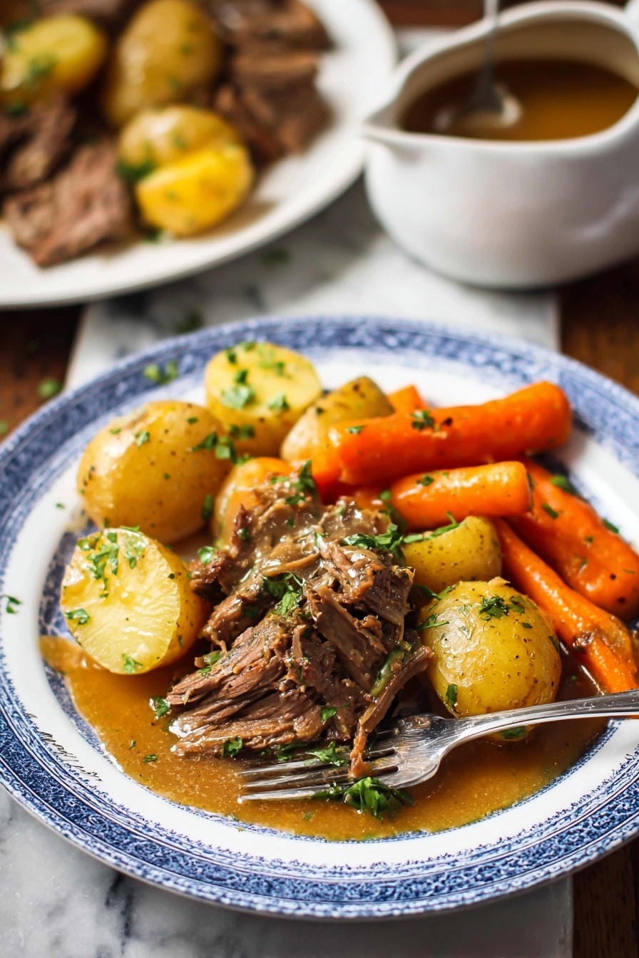Slow Cooker Pot Roast with Root Vegetables and Red Wine Gravy, hearty beef stew, slow cooker beef recipes, comfort food dinner ideas, easy pot roast recipes - A white plate with a blue rim holds a hearty meal featuring three main layers: golden brown pieces of cooked beef in the center topped with chopped green herbs, tender yellow baby potatoes scattered around the beef, and bright orange carrot sticks positioned near the back. A golden brown sauce with a smooth texture lightly covers parts of the beef and potatoes. A silver fork rests on the plate's edge. In the background, there is a white marbled surface with a blurred white plate containing more beef and potatoes, and a white saucepan with brown sauce on the left side. The overall scene has warm, natural lighting. photo taken with an iphone --ar 2:3 --v 7