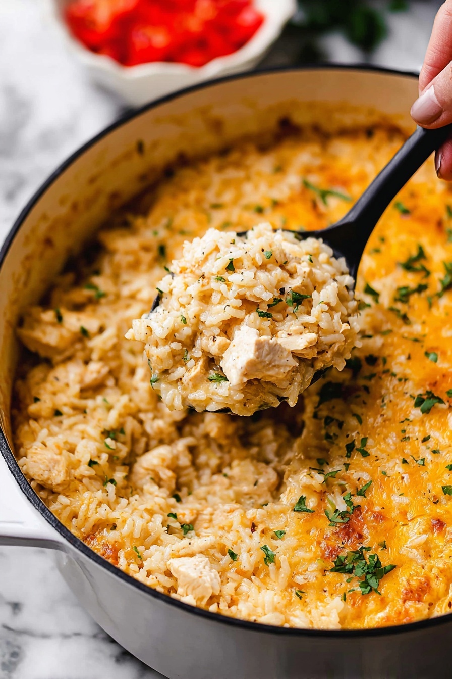 One Pot Queso Chicken and Rice, cheesy chicken and rice skillet, creamy chicken and rice dinner, easy cheesy chicken casserole, one pot cheesy chicken recipe - This image shows a close-up of a white pot filled with a creamy, cheesy rice dish. The dish has one main layer of cooked rice mixed with small pieces of chicken and sprinkled with chopped green herbs. The rice looks soft and slightly orange-yellow from the cheese sauce that covers it evenly, with some melted cheese visible on top near the edges. A black spoon lifted by a woman's hand holds a scoop of the rice mixture in the center of the pot. The background shows a blurred white bowl with chopped red tomatoes. The whole scene is set on a white marbled surface. photo taken with an iphone --ar 2:3 --v 7
