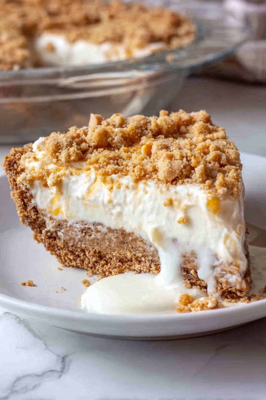 Angel Pecan Pie, light pecan pie, fluffy pecan pie, crunchy cracker crust pecan pie, festive pecan pie dessert - A close-up view of a thick, light brown crust with cracks, forming the base layer in a clear glass pie dish, on a white marbled surface. On top of the crust, a fluffy, white cream layer is being spread evenly, poured from a bowl using a blue spatula held by a woman's hand. The cream is soft and smooth, with gentle folds as it lands on the crust, creating a thick second layer. The background shows a blurred maroon fabric. Photo taken with an iphone --ar 2:3 --v 7