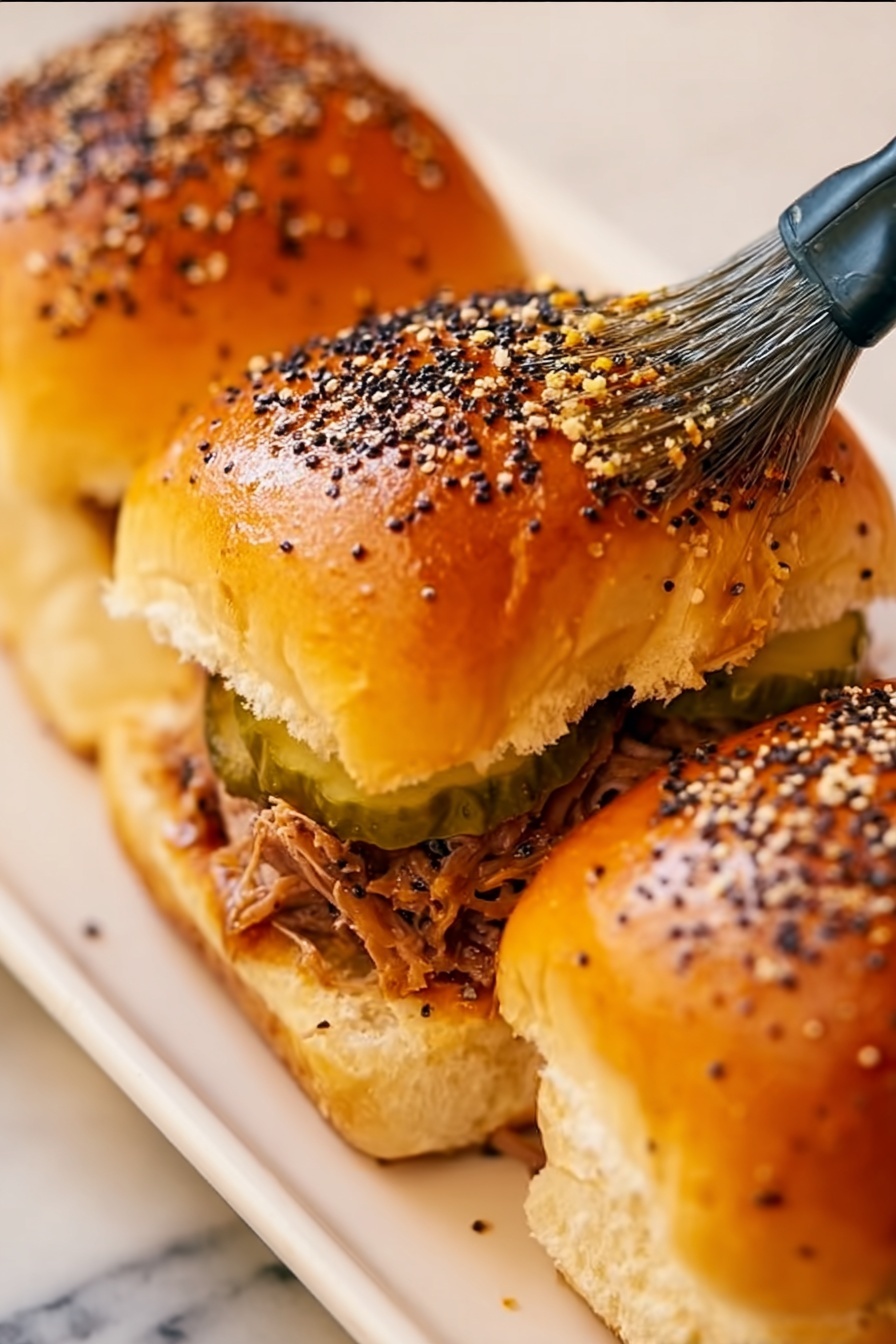 Cuban Pork Sliders, Cuban Pork Sliders Recipe, easy Cuban sliders, pulled pork sliders, party sliders - The image shows a close-up of a golden brown bread roll cluster with a shiny surface, sprinkled with white sesame seeds and black poppy seeds. There is a yellow silicone brush with black details gently spreading a glaze on the soft tops of the rolls. The bread rolls appear fluffy and slightly puffy, with visible seams and light texture. The background is a white marbled surface. photo taken with an iphone --ar 2:3 --v 7