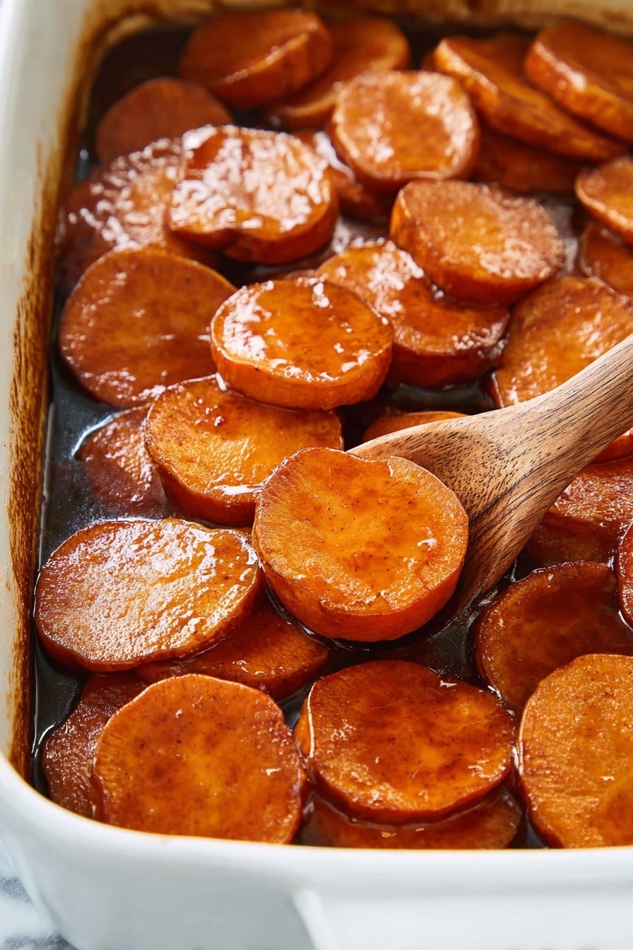 Southern Candied Yams, soul food side dish, sweet potato casserole, holiday yams recipe, easy Southern yam recipe - The image shows a close-up of a white baking dish filled with thick, round slices of sweet potatoes, cooked in a rich, shiny brown glaze that coats each slice with a sticky texture. The sweet potato slices are arranged in a slightly overlapping layer, showing their smooth and glossy surface with a warm orange-brown color. A wooden spoon is partially visible on the right side, scooping some slices, adding a natural wooden texture to the scene. The background and surface are a white marbled texture. photo taken with an iphone --ar 2:3 --v 7