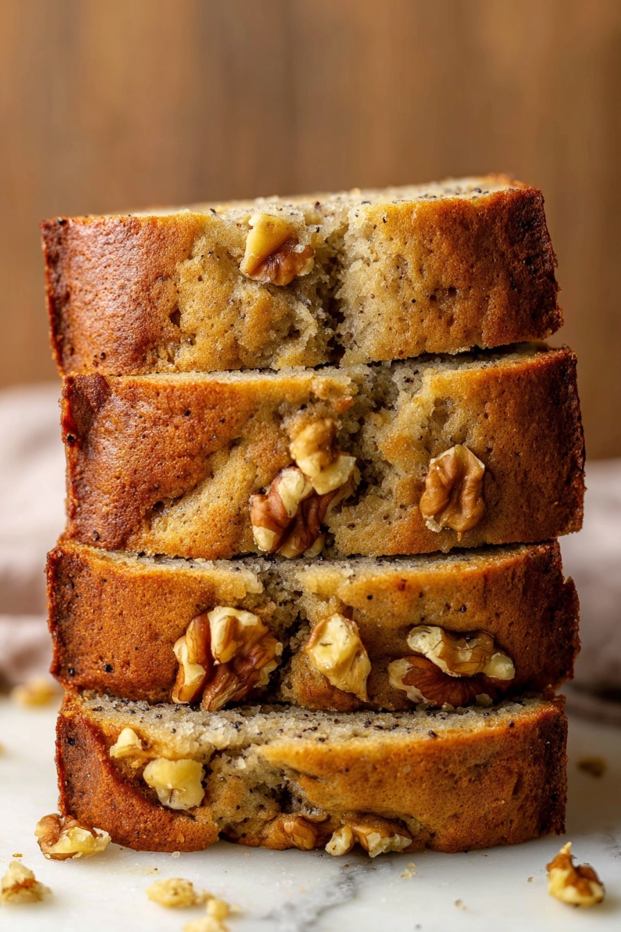 Best Vegan Banana Bread, vegan banana bread recipe, plant-based banana bread, moist banana bread, vegan baking recipes - A stack of four thick banana bread slices sits on a white marbled surface, each slice showing a soft, moist interior with a light brown color and speckles of dark spots from bananas. The crust is golden brown and slightly crumbly with several walnut pieces embedded both on the top and inside the bread. Some walnuts are well visible on the top edges, adding texture. The bread has a homemade rustic look with a few cracks and uneven parts along the sides and top. The background is a warm wooden texture blurred out softly. Photo taken with an iphone --ar 2:3 --v 7