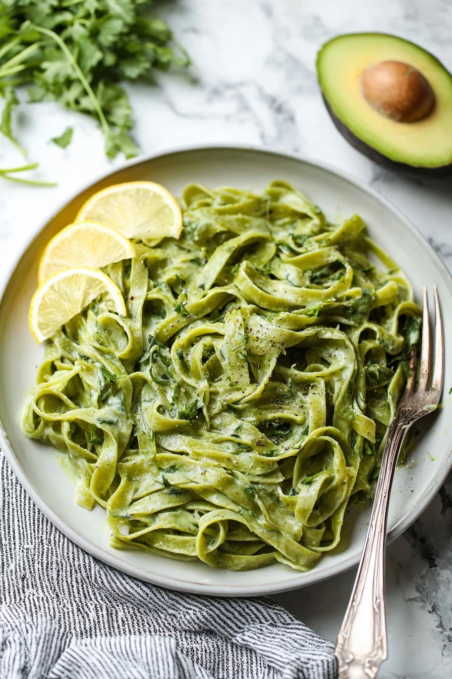 Avocado Lemon Pesto, avocado lemon sauce, homemade pesto, vegan pesto sauce, fresh green sauce - A clear blender jar with four sharp blades at the bottom contains a thick, smooth mixture of bright green color with a slight creamy texture. The blender base beneath is black with a large round silver knob in the center. The jar handle is transparent with a blue tint, positioned to the right, and the whole scene is set on a white marbled surface. photo taken with an iphone --ar 2:3 --v 7