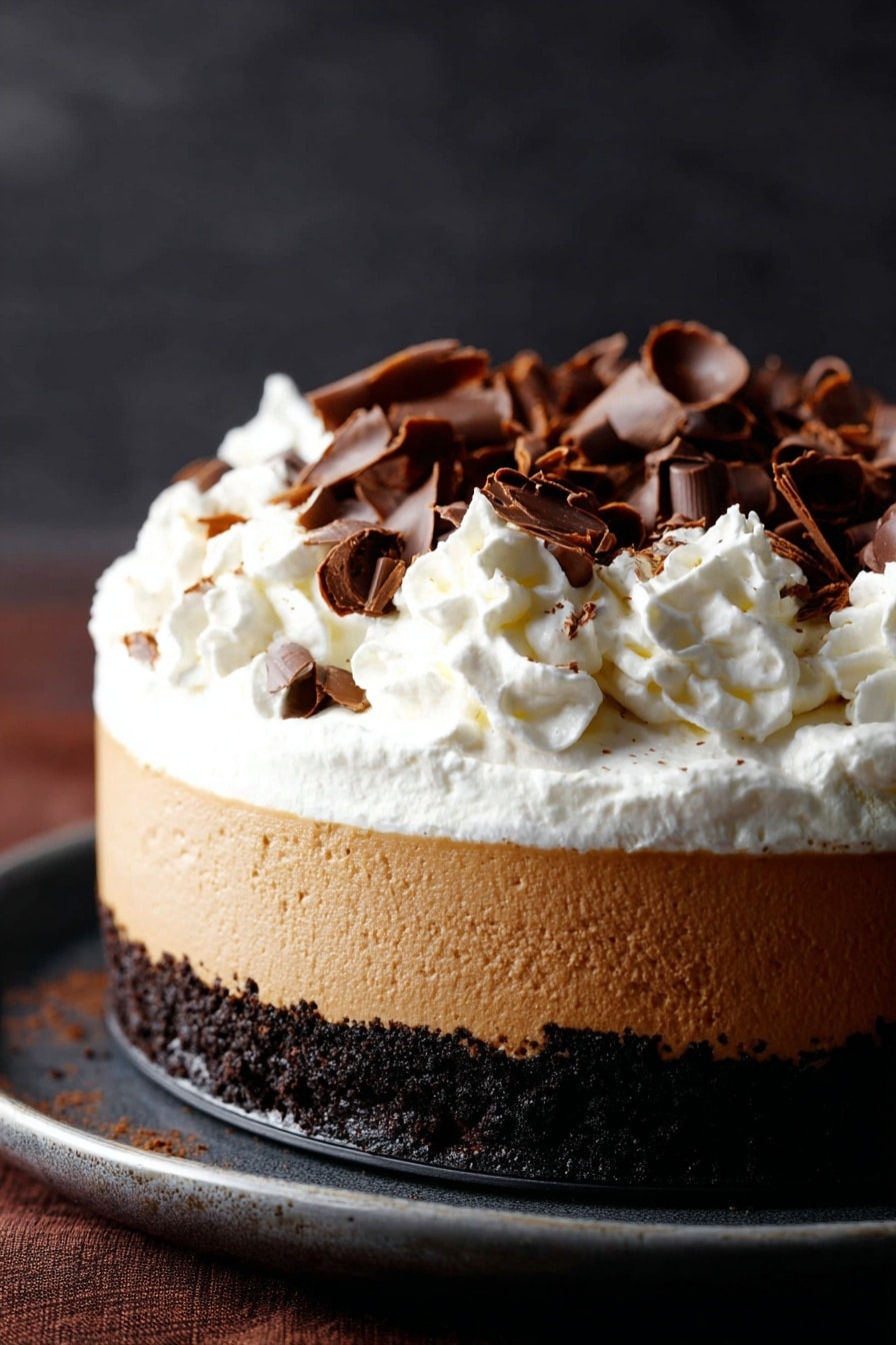 Chocolate Pumpkin Cheesecake with Bourbon Whipped Cream, fall dessert recipes, pumpkin cheesecake with chocolate, bourbon whipped cream dessert, easy autumn holiday treats - A three-layer dessert is shown, starting with a dark crumbly chocolate base at the bottom, followed by a thick smooth light brown creamy layer in the middle, topped with a generous fluffy white whipped cream layer. The whipped cream is decorated with scattered dark brown curled chocolate pieces. The dessert sits on a dark surface with a soft dark background. photo taken with an iphone --ar 2:3 --v 7