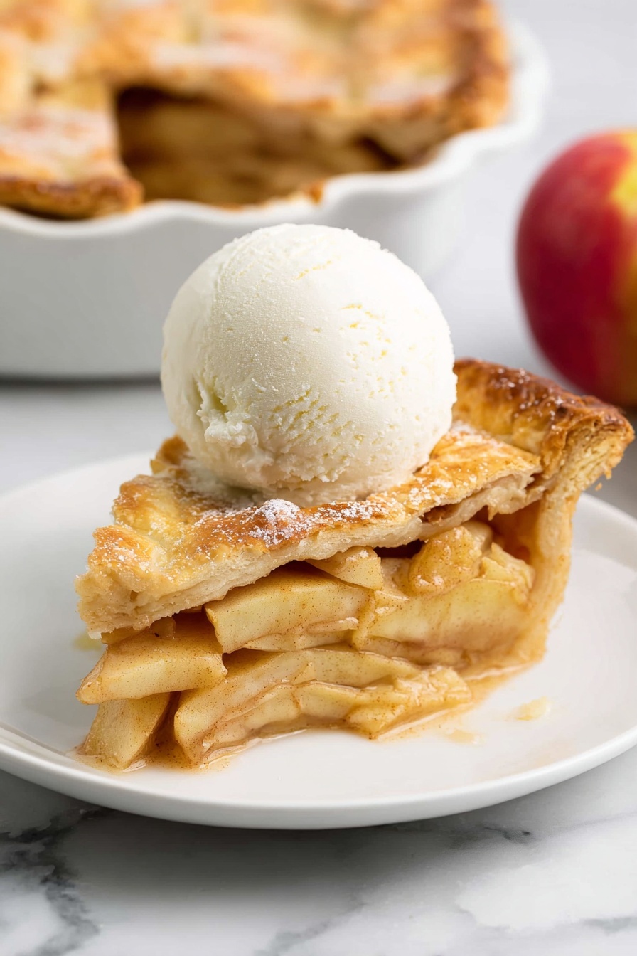 Perfect Vegan Apple Pie Recipe, vegan apple pie, dairy-free apple pie, best vegan dessert, easy vegan pie - A slice of apple pie sits on a white plate with a white marbled background. The pie has two layers of golden-brown crust, one on the bottom and one on top, with the top crust slightly cracked and sprinkled with sugar. Between the crust layers are thin slices of light yellow apples mixed with a brown cinnamon spice, visible in the thick filling. On top of the pie slice is a smooth, round scoop of white vanilla ice cream that starts to melt slightly around the edges. In the background, part of the full apple pie in a white dish and a red apple are faintly seen. Photo taken with an iphone --ar 2:3 --v 7