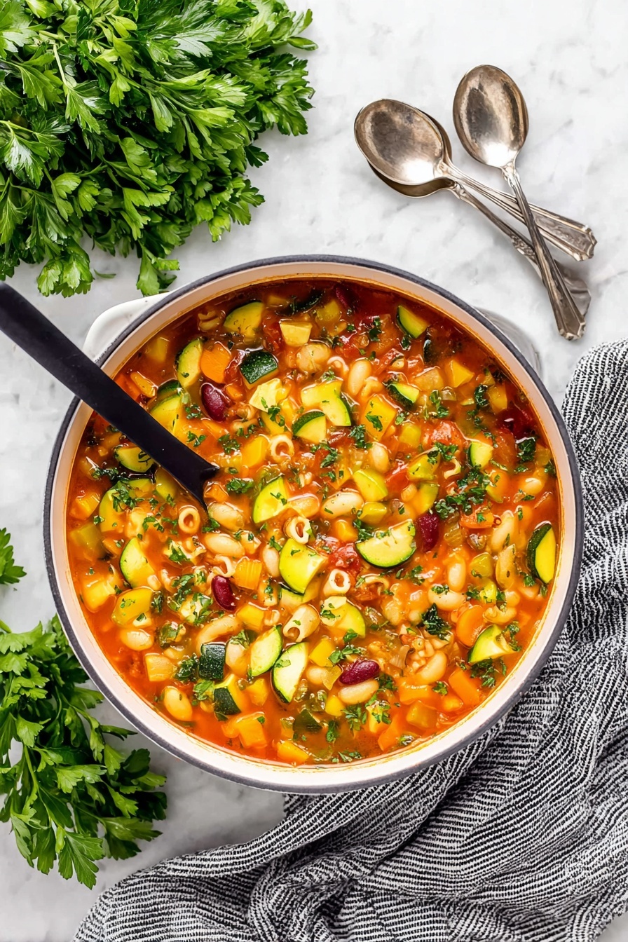 Easy Minestrone Soup, hearty vegetable soup, quick Italian soup, healthy minestrone recipe, comforting veggie soup - A close-up of a white pot filled with colorful minestrone soup, showing about five layers of ingredients in a light red broth. The soup contains small pasta shells, dark red kidney beans, orange carrot cubes, yellow and green zucchini slices, green celery pieces, and diced tomatoes. A ladle is lifting a scoop of soup with a mix of these ingredients, showcasing their textures and colors. The background has a white marbled texture with some green herb leaves visible around the pot. Photo taken with an iphone --ar 2:3 --v 7