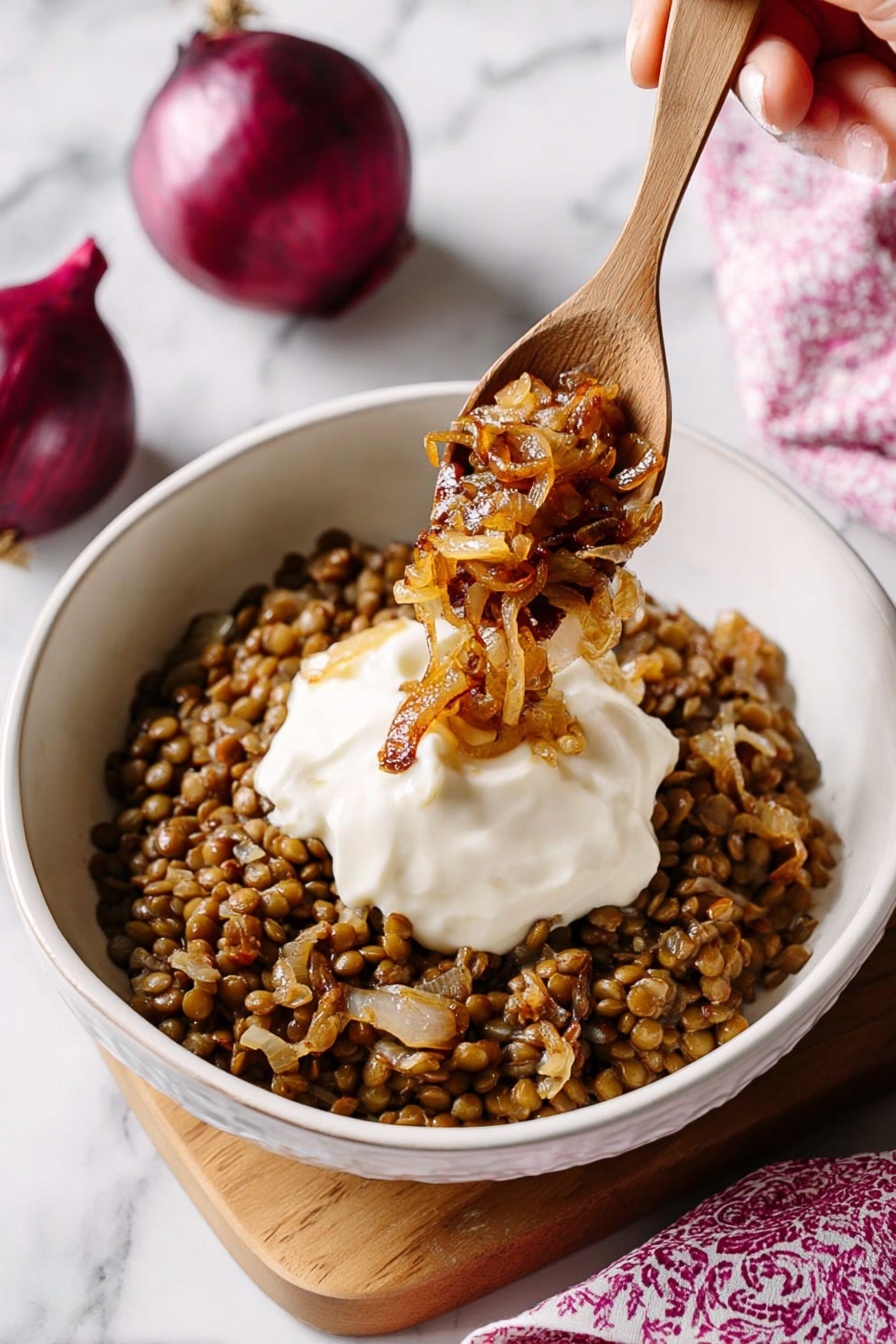 Easy Lentil and Rice Mujadara, Lentil and Rice Mujadara, vegetarian Middle Eastern dishes, hearty plant-based meals, simple Mujadara recipe - A white bowl filled with a base layer of cooked lentils mixed with small pieces of caramelized onion, creating a brown and slightly textured bed. On top, there is a smooth, thick white dollop of sauce centered in the bowl. A wooden spoon is positioned above the bowl, held by a woman's hand, scooping some golden-brown caramelized onions over the sauce. The background features a white marbled surface with two whole red onions partially visible in the upper right corner and a softly blurred pink patterned cloth in the lower right. photo taken with an iphone --ar 2:3 --v 7