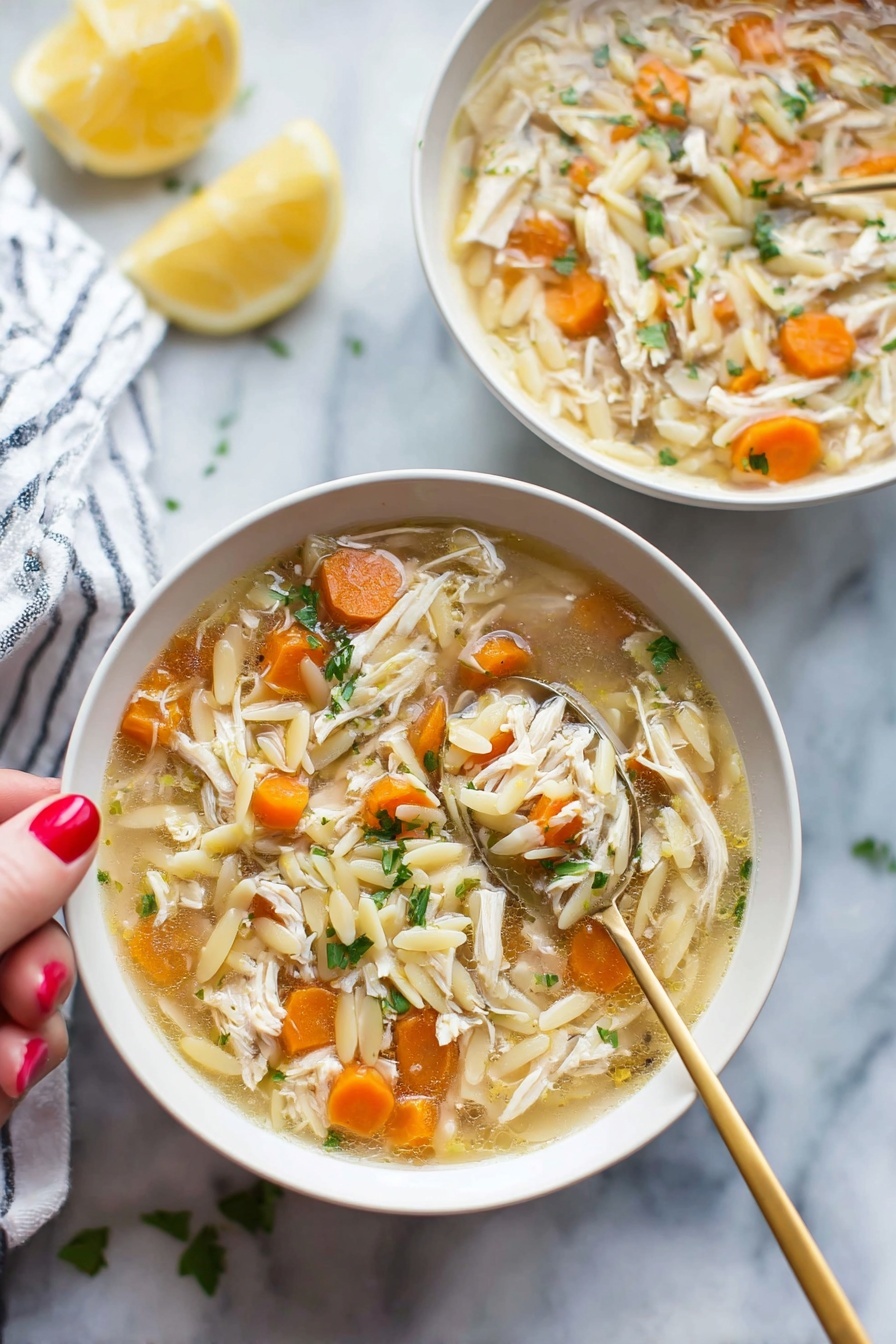 Lemon Chicken Soup, healthy lemon chicken soup, comforting chicken soup with lemon, easy lemon chicken soup, bright flavorful chicken soup - Two white bowls filled with soup sit on a white marbled surface, each bowl holding a mix of shredded light brown chicken, small round orange carrot slices, and pale yellow orzo pasta floating in a light broth. Bright green herbs are sprinkled throughout the soup, adding fresh color. A gold spoon is held by a woman's hand with red painted nails, lifting a spoonful of soup from the bowl in the front, showing a clear view of the ingredients. In the background, a lemon half and a white-and-blue striped cloth are softly out of focus. photo taken with an iphone --ar 2:3 --v 7