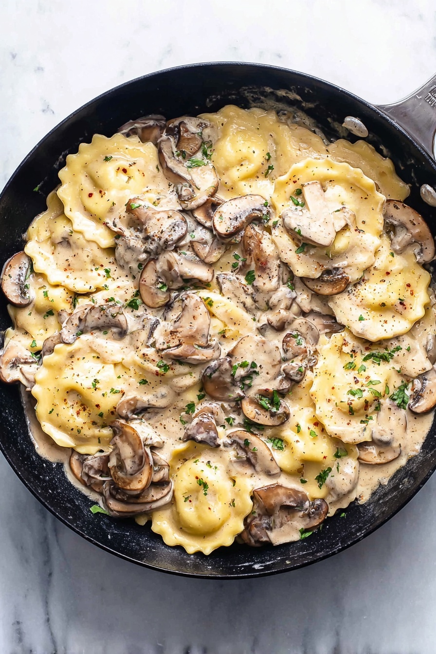 Creamy Mushroom Ravioli Skillet, mushroom ravioli dinner, quick mushroom pasta, easy creamy ravioli recipe, one-pan mushroom meal - The image shows a black pan filled with a creamy mushroom sauce and round ravioli pasta. The ravioli are light yellow with slightly ruffled edges, spread throughout the pan. Layered on and around the pasta are sliced mushrooms in different shades of brown and beige, mixed with small green parsley bits for garnish. The creamy sauce is thick, light beige, and covers the ravioli and mushrooms evenly, with visible black pepper flecks on top. The pan is placed on a white marbled surface, and the overall scene is bright and clean. photo taken with an iphone --ar 2:3 --v 7