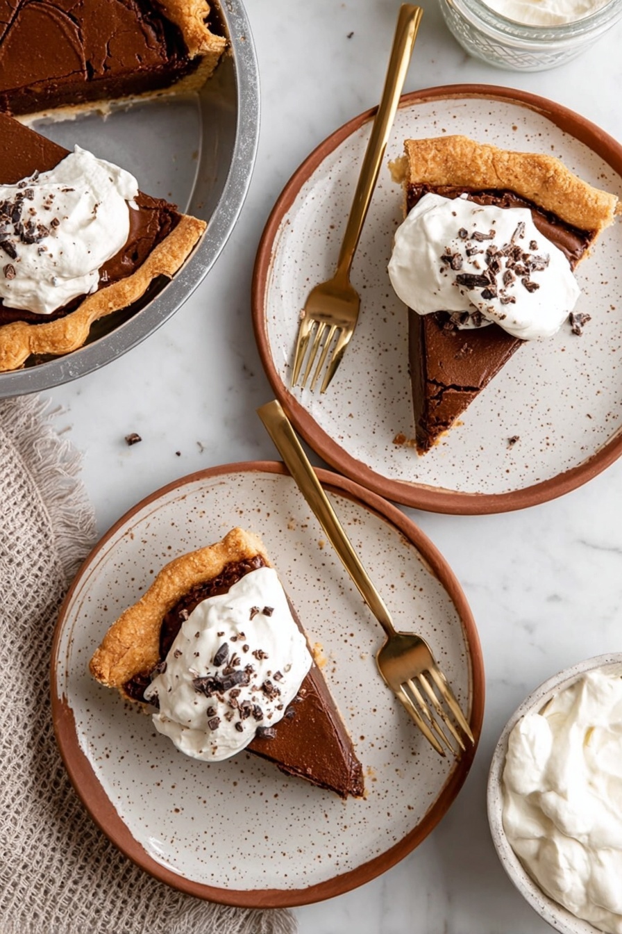 Fudgy Chocolate Brownie Pie, chocolate brownie pie, decadent brownie tart, chocolate dessert, homemade brownie pie - A slice of chocolate pie with three visible layers sits in a metal pie pan: the bottom layer is a light golden flaky crust, the middle layer is a thick dark brown chocolate filling, and the top layer is a cracked lighter brown chocolate crust. On top of the slice is a dollop of white whipped cream sprinkled with small chocolate shavings. The pie pan rests on a metal cooling rack over a white marbled surface. In the background, there is a blurred white container and a white bowl with more chocolate pie. photo taken with an iphone --ar 2:3 --v 7