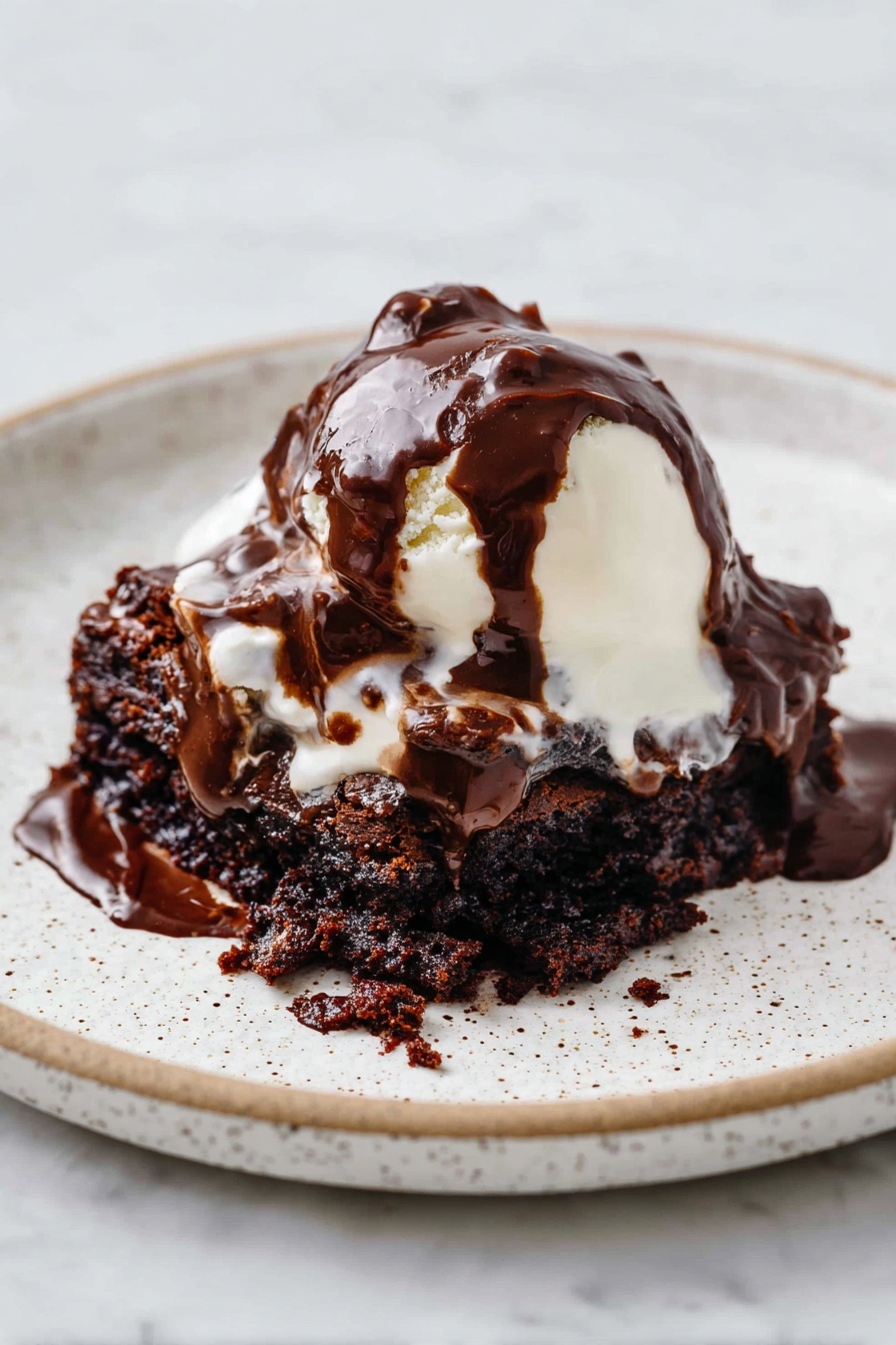 Decadent Hot Fudge Cake, hot fudge cake recipe, chocolate dessert, gooey chocolate cake, self-saucing pudding - A white speckled plate holds a dessert with three main layers. The bottom layer is a dark brown, moist chocolate cake with a rough, crumbly texture. On top of this is a soft, white scoop of melting ice cream that is smooth and creamy. The top layer is thick, glossy dark chocolate sauce, generously poured over the ice cream and cake, flowing and blending into the layers below. The plate sits on a white marbled surface. photo taken with an iphone --ar 2:3 --v 7
