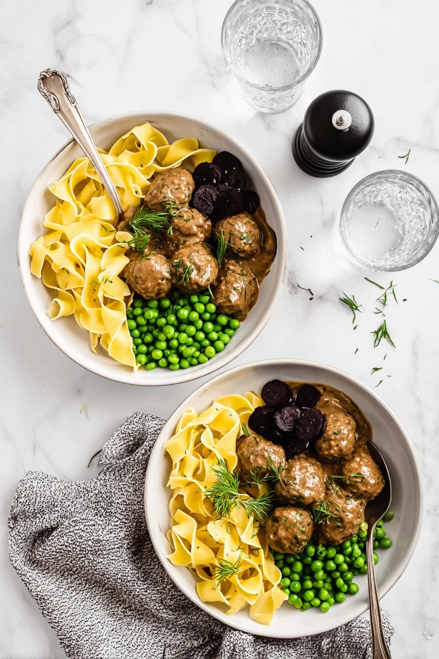Swedish Meatballs with Creamy Gravy, Swedish Meatballs, Creamy Gravy Recipe, Comfort Food Recipes, Easy Swedish Meatballs - Two white bowls placed on a white marbled surface hold a meal of three layers each. The first layer in each bowl is wide, flat yellow pasta ribbons arranged loosely in a pile on one side with a light sprinkle of herbs. The second layer beside the pasta is a small heap of bright green peas. The third layer, next to the peas, consists of brown meatballs covered in a smooth, creamy brown sauce, garnished with fresh green herbs and one or two dark purple pickled elements. Each bowl has a silver spoon resting inside. A black pepper grinder, a speckled gray cloth, and two clear glasses of water are also arranged on the white marbled surface. Photo taken with an iphone --ar 2:3 --v 7