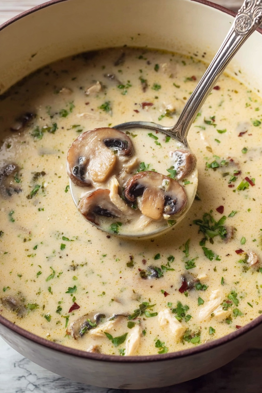 Creamy Chicken Mushroom Soup, hearty mushroom chicken soup, comforting chicken and mushroom dinner, easy creamy chicken mushroom recipe, cozy mushroom chicken bowl - A close-up view of a light creamy soup filled with sliced mushrooms and small pieces of chicken, sprinkled with chopped green herbs and tiny dried herbs throughout. The soup has a smooth texture with floating bits of green and brown, and a silver ladle scoops a portion showing three layers of sliced mushrooms, chicken bits, and the creamy broth all mixed. The soup is in a deep white bowl, resting on a white marbled surface. Photo taken with an iphone --ar 2:3 --v 7