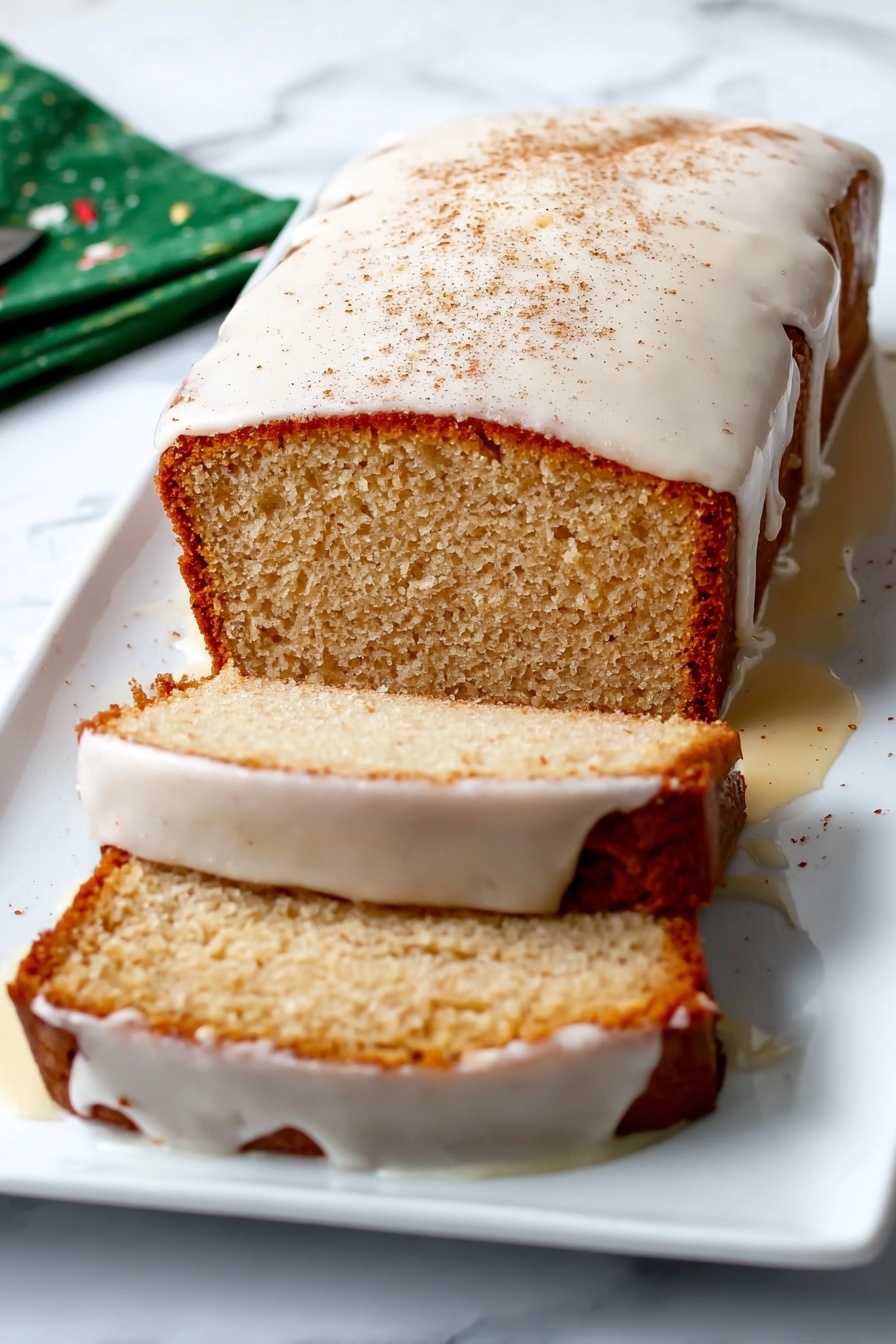Eggnog Bread Holiday Bread Festive Eggnog Bread Christmas Bread Easy Eggnog Bread - A loaf cake with a light brown crust sits on a white rectangular plate against a white marbled surface. The cake is sliced twice, with two visible slices lying flat next to the main loaf. A thick white glaze covers the top of the cake, dripping over the sides and partly onto the plate, with a light dusting of cinnamon on top. The inside of the cake is a soft beige color with a slightly crumbly texture. Photo taken with an iphone --ar 2:3 --v 7