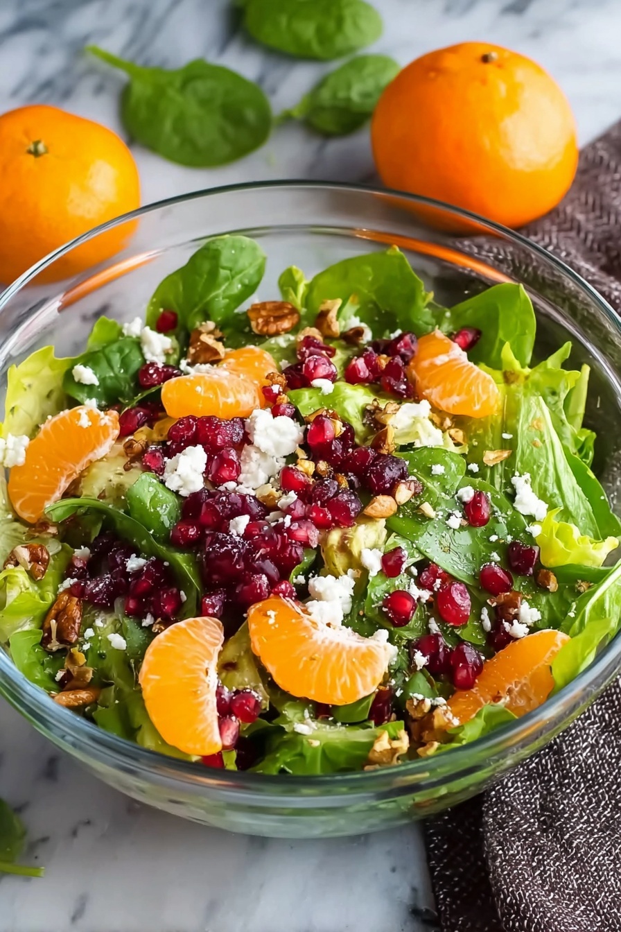 Winter Citrus Salad with Pomegranate and Feta, citrus and pomegranate salad, winter fruit salad, refreshing citrus salad, healthy winter salad - A clear glass bowl filled with a colorful salad, showing a mix of green leafy spinach and lettuce as the base layer, topped with bright orange mandarin slices scattered evenly, followed by deep red pomegranate seeds sprinkled throughout, and small white crumbles of cheese spread on top. Bits of brown nuts add texture and are scattered on the salad. The bowl is placed on a white marbled surface, with two whole mandarins and green leaves blurred in the background, and a gray textured cloth to the right, photo taken with an iphone --ar 2:3 --v 7