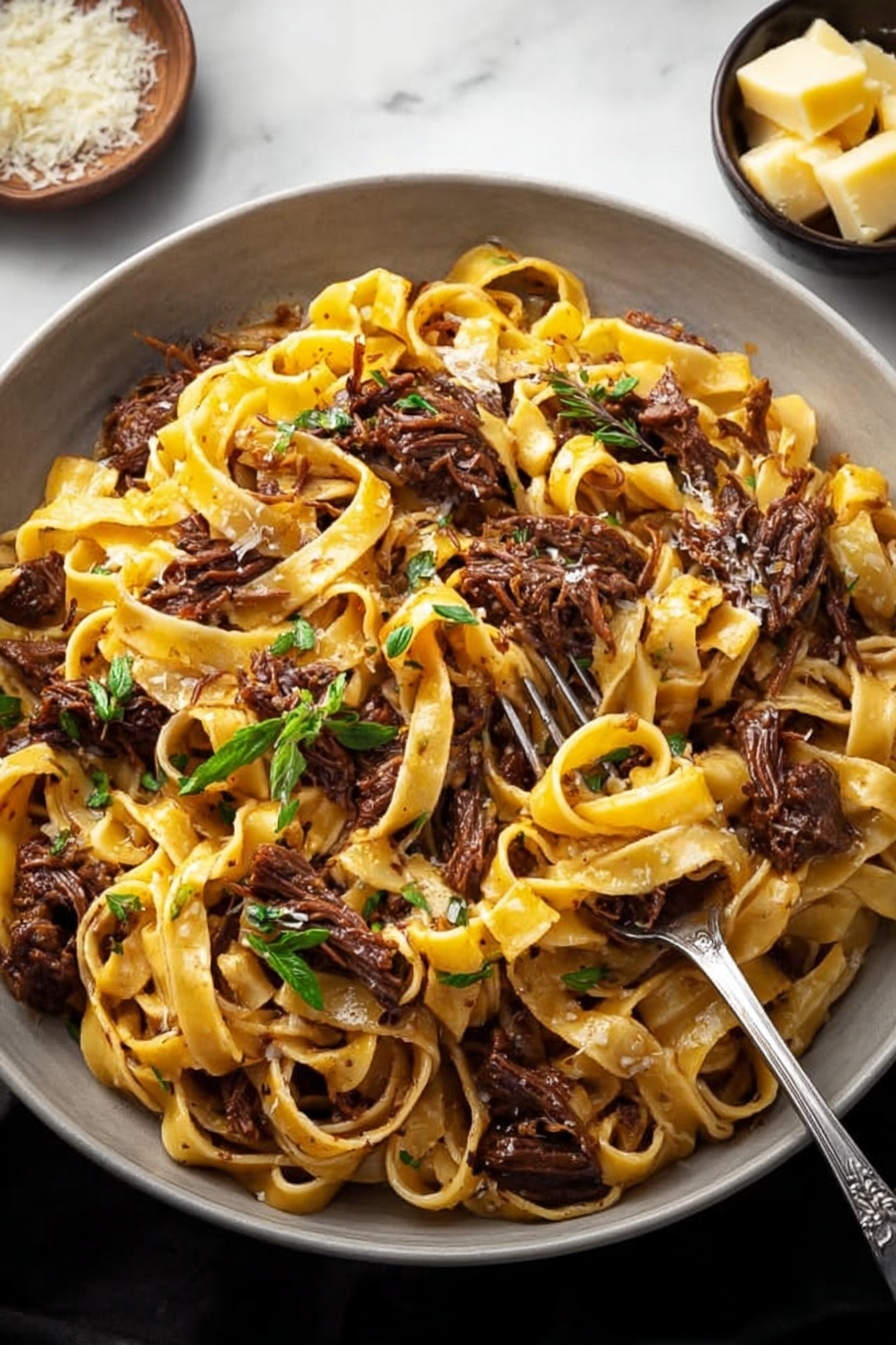 Short Rib Ragu Pasta, Braised Short Rib Pasta, Easy Short Rib Ragu, Comforting Pasta Recipes, Hearty Beef Pasta - A large white bowl filled with a generous serving of tagliatelle pasta mixed with shredded dark brown meat pieces. The pasta is light golden yellow with a slight shine, entwined among the tender meat chunks. Fresh green herb leaves are scattered on top, adding a touch of color and freshness. A small metal fork is placed inside the bowl, partly twirling some pasta and meat. In the background, a small bowl holds chunks of light yellow cheese, and everything is set against a white marbled surface. Photo taken with an iphone --ar 2:3 --v 7