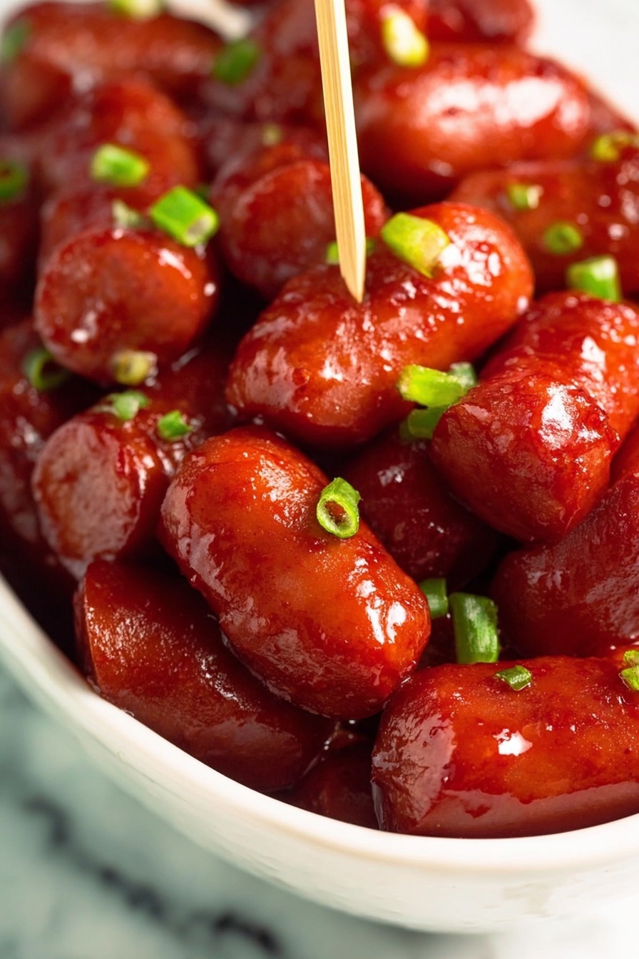 Crockpot BBQ Little Smokies, easy party snacks, slow cooker appetizers, smoky cocktail sausages, quick game day bites - A close-up view of a white bowl filled with small red sausages covered in a shiny sauce. The sausages are packed closely together, some skewered with a wooden toothpick standing upright in the center. Small pieces of bright green chopped scallions are sprinkled evenly over the sausages, adding a fresh touch. The glossy texture of the sauce highlights the smooth surface of the sausages, making them look juicy and flavorful. The bowl is placed on a surface with a white marbled texture photo taken with an iphone --ar 2:3 --v 7