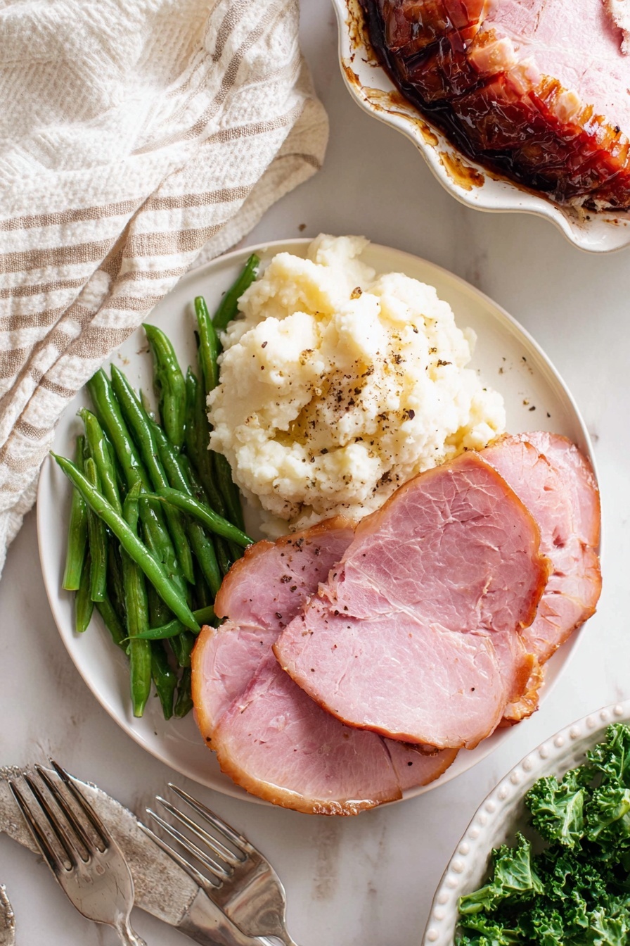 Baked Glazed Ham, glazed ham recipe, baked ham with glaze, holiday ham ideas, easy baked ham - A white round plate shows a simple meal with three parts: green beans on the top left, fluffy mashed potatoes with some black pepper on the bottom left, and two thick slices of pink ham on the right, with a light brown edge. The plate sits on a white marbled surface with a white and beige striped cloth on the top left and two silver forks below the plate. On the right top corner, there is a partial view of another white round plate with a slice of ham and green beans. In the bottom right, a white dish filled with sliced glazed ham resting on green leafy kale is partially shown. photo taken with an iphone --ar 2:3 --v 7