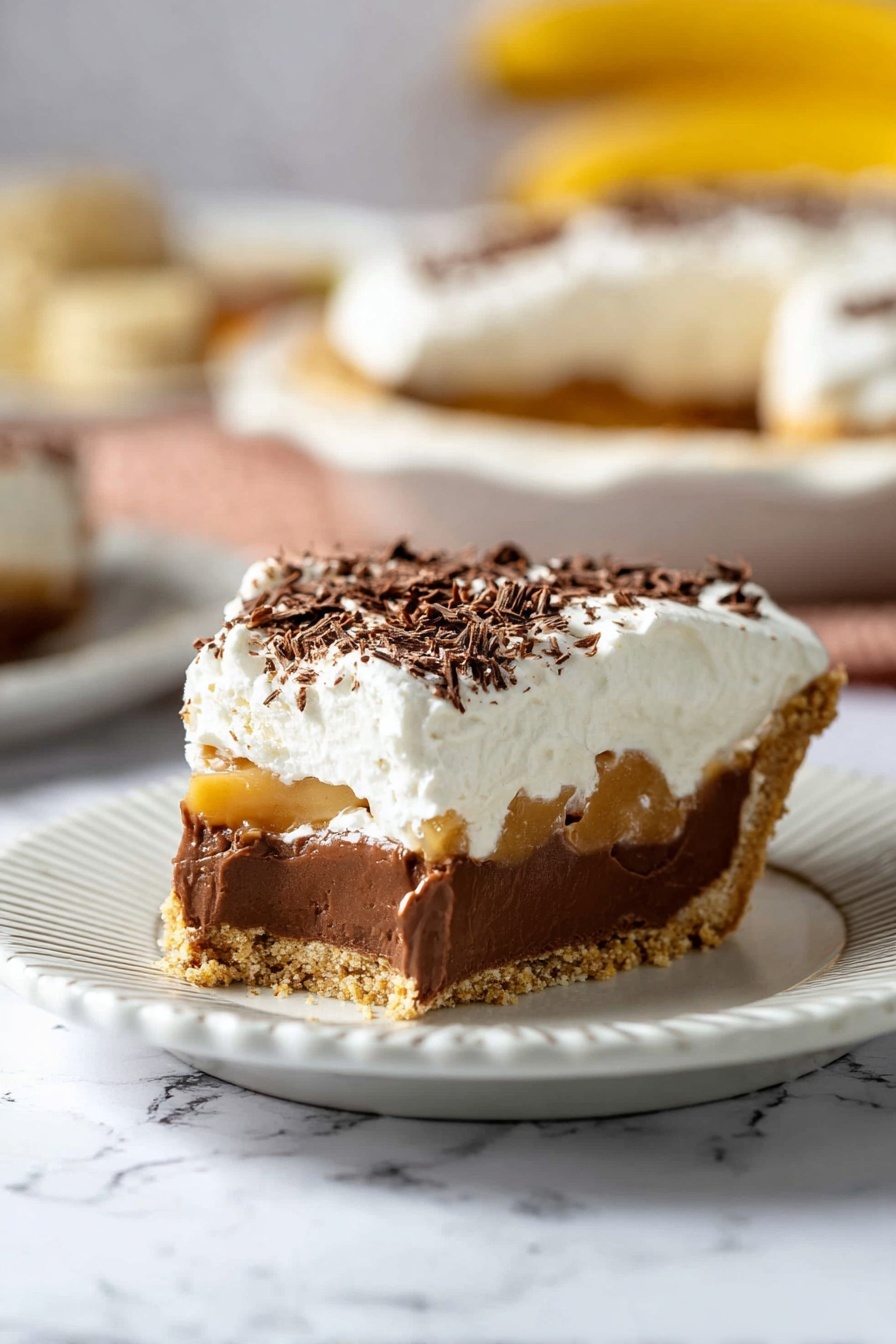 Banoffee Pie with Caramel and Banana, easy banoffee pie recipe, caramel banana dessert, how to make banoffee pie, simple dessert ideas - The image shows a slice of pie on a white plate with ridged edges, placed on a white marbled surface. The pie has four layers: at the bottom is a crumbly, light brown crust; above it is a thick, smooth, dark brown chocolate layer; then a thin layer of caramel with slice pieces visible inside; and on top is a thick, fluffy white cream layer sprinkled lightly with dark brown chocolate shavings. The background is softly blurred, showing more pie and some bananas. Photo taken with an iphone --ar 2:3 --v 7