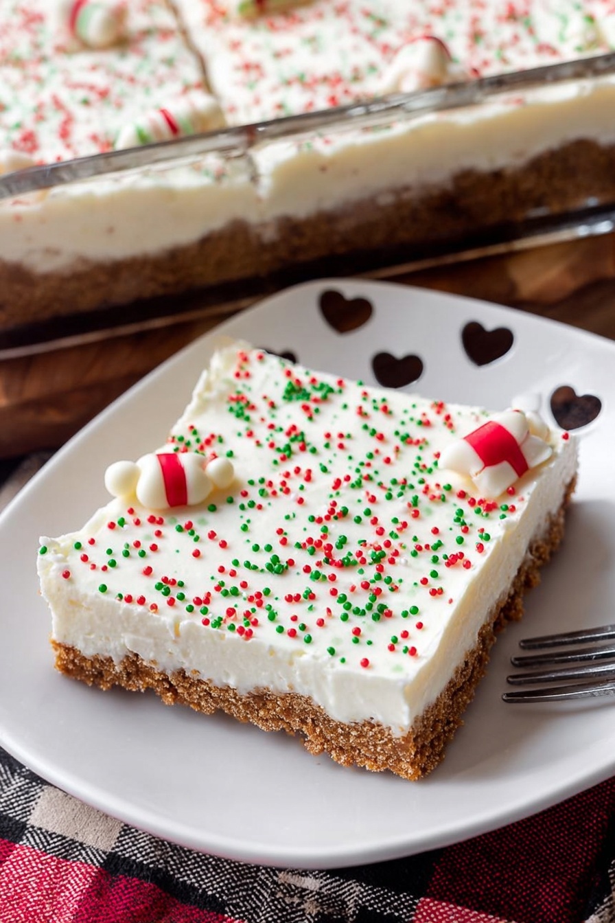 Spiced Gingerbread Cookie Bars, gingerbread cookie bars, holiday cookie bars, festive spice dessert, easy gingerbread bars - A square dessert bar is shown on a white plate with small heart-shaped cutouts around the edge. The dessert has two clear layers: the bottom layer is a brown, crumbly crust, and the top layer is a thick, smooth, white cream. The white layer is decorated with small round sprinkles in red, green, and white colors, with a pair of white candy pieces with red and green stripes placed near the center. The dessert and plate sit on a wooden surface with a red, black, and beige checkered cloth nearby. Part of a glass baking dish filled with the same dessert and a smiling ceramic cup are visible in the background. A woman's hand holds a fork resting on the plate. photo taken with an iphone --ar 2:3 --v 7
