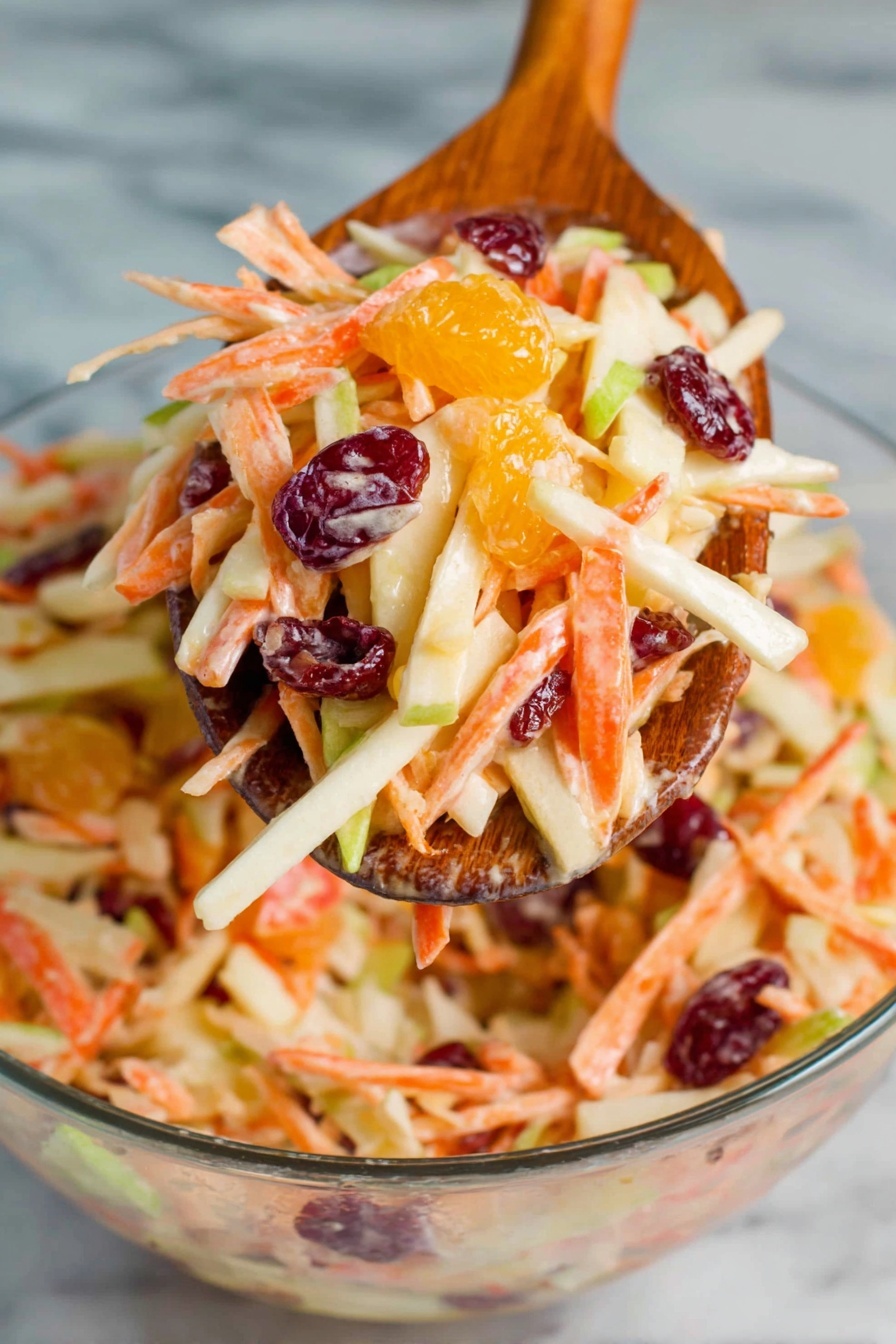 Carrot Apple Salad with Cranberries and Mandarins, healthy fruit salad idea, easy autumn salad, fresh fruit salad recipe, colorful citrus carrot salad - A wooden spoon holds a colorful mix of salad with several layers: thin, long orange carrot strips, off-white apple slices, small bright orange mandarin pieces, and shiny dark red dried cranberries, all coated in a creamy dressing. Below, a clear glass bowl is filled with the same mix, showing a dense, fresh, and juicy texture with different colors like green apple skin peeking through. The background is a white marbled surface. photo taken with an iphone --ar 2:3 --v 7
