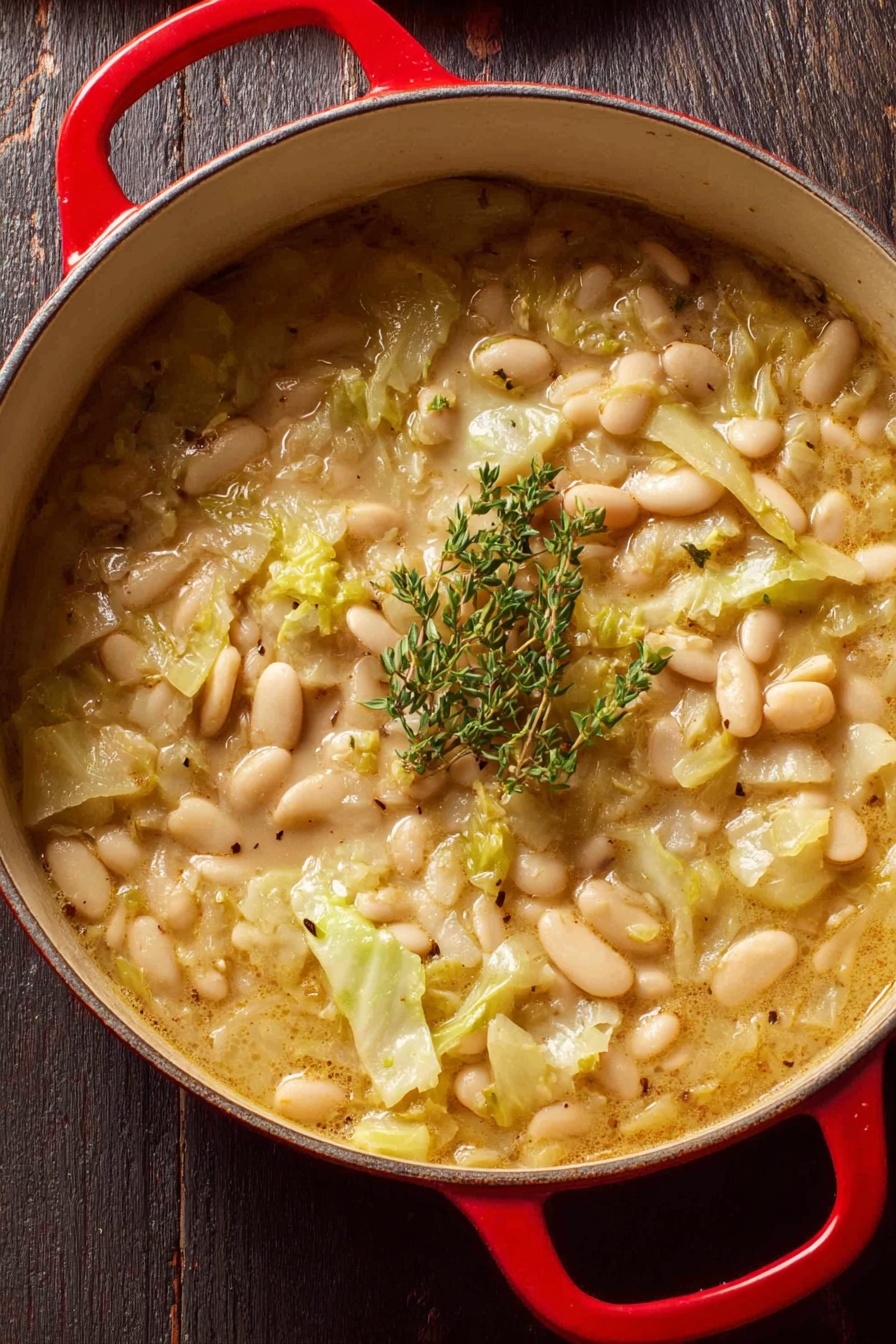 Creamy Butter Beans with Leeks, butter beans with leeks, savory leek and bean dish, comforting vegetarian main, easy creamy bean recipe - A close-up view of a red pot filled with a thick stew made of white beans and chopped light green cabbage in a creamy broth. The stew shows soft textures with some beans floating on top mixed with pieces of cabbage, and it is garnished with a small bunch of fresh green thyme placed in the center. The pot is resting on a dark wooden surface. photo taken with an iphone --ar 2:3 --v 7