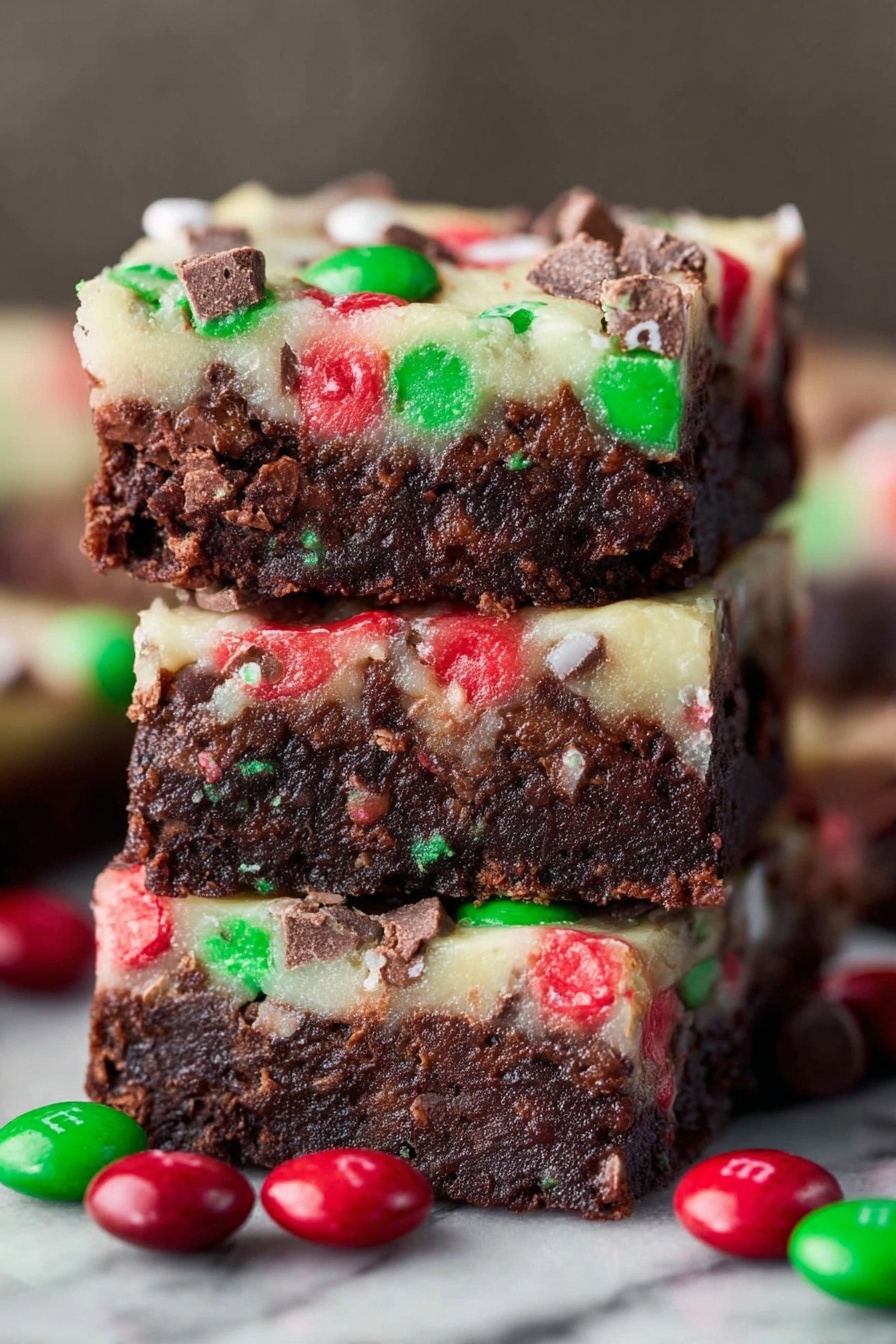 Christmas Brownie Bars with M&Ms, festive brownie dessert, holiday chocolate bars, Christmas treats with M&Ms, easy holiday brownie recipe - The image shows a close-up of three stacked dessert bars with two clear layers. The bottom layer is thick, dense, and dark brown with a fudgy texture. The top layer is thinner and creamy white, embedded with red and green candy pieces and small chocolate chunks scattered throughout. Around the stack, several red and green round candies with a shiny shell are scattered. The background has a white marbled texture. photo taken with an iphone --ar 2:3 --v 7