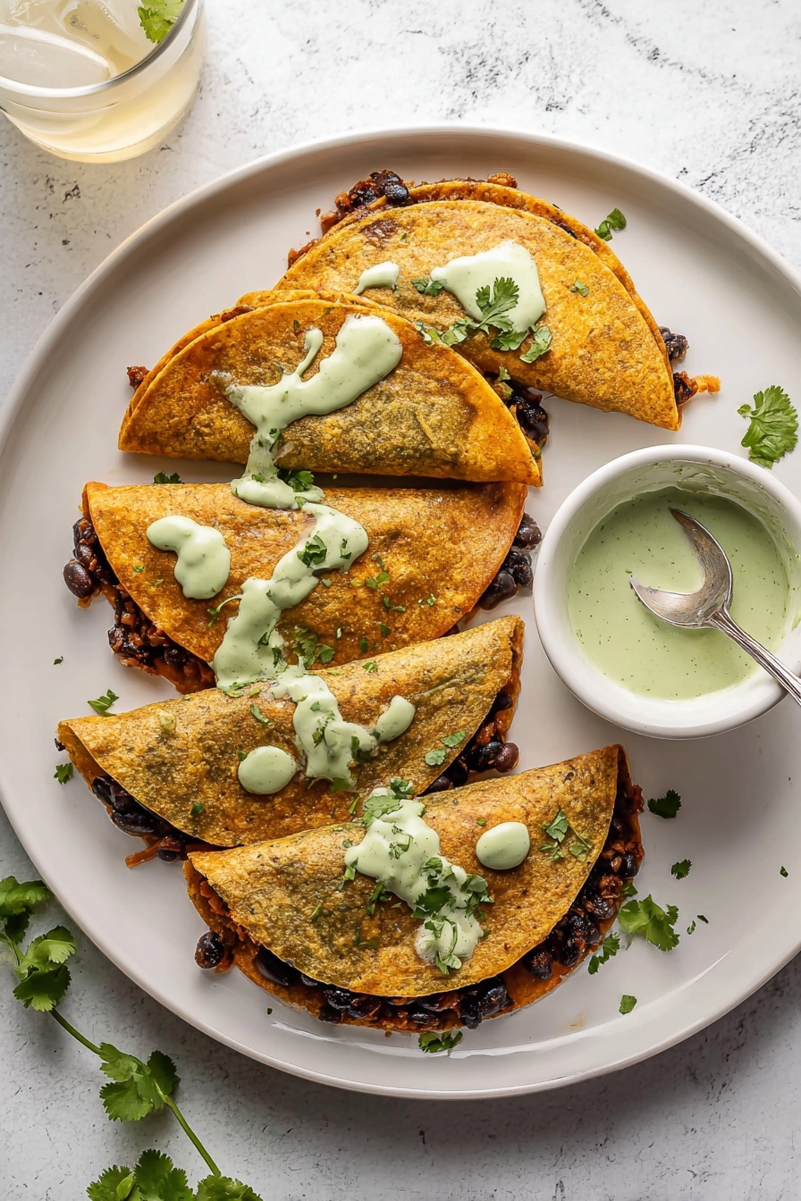Crispy Baked Turkey Tacos with Avocado Sauce, Turkey taco recipes, baked taco ideas, easy turkey tacos, healthy taco dinner - The image shows four folded golden-brown tortillas on a white plate with a white marbled surface background. Each tortilla is filled with a dark layer of what looks like cooked black beans mixed with a brown filling, peeking out slightly from the open edges. There are light green creamy sauce dollops spread unevenly over the top of the tortillas with some dripping down the sides. Fresh green cilantro leaves are scattered around the plate and a small white bowl with more of the light green sauce and a spoon inside it sits on the right side. A glass with ice and a light-colored drink is at the top left corner. Photo taken with an iphone --ar 2:3 --v 7