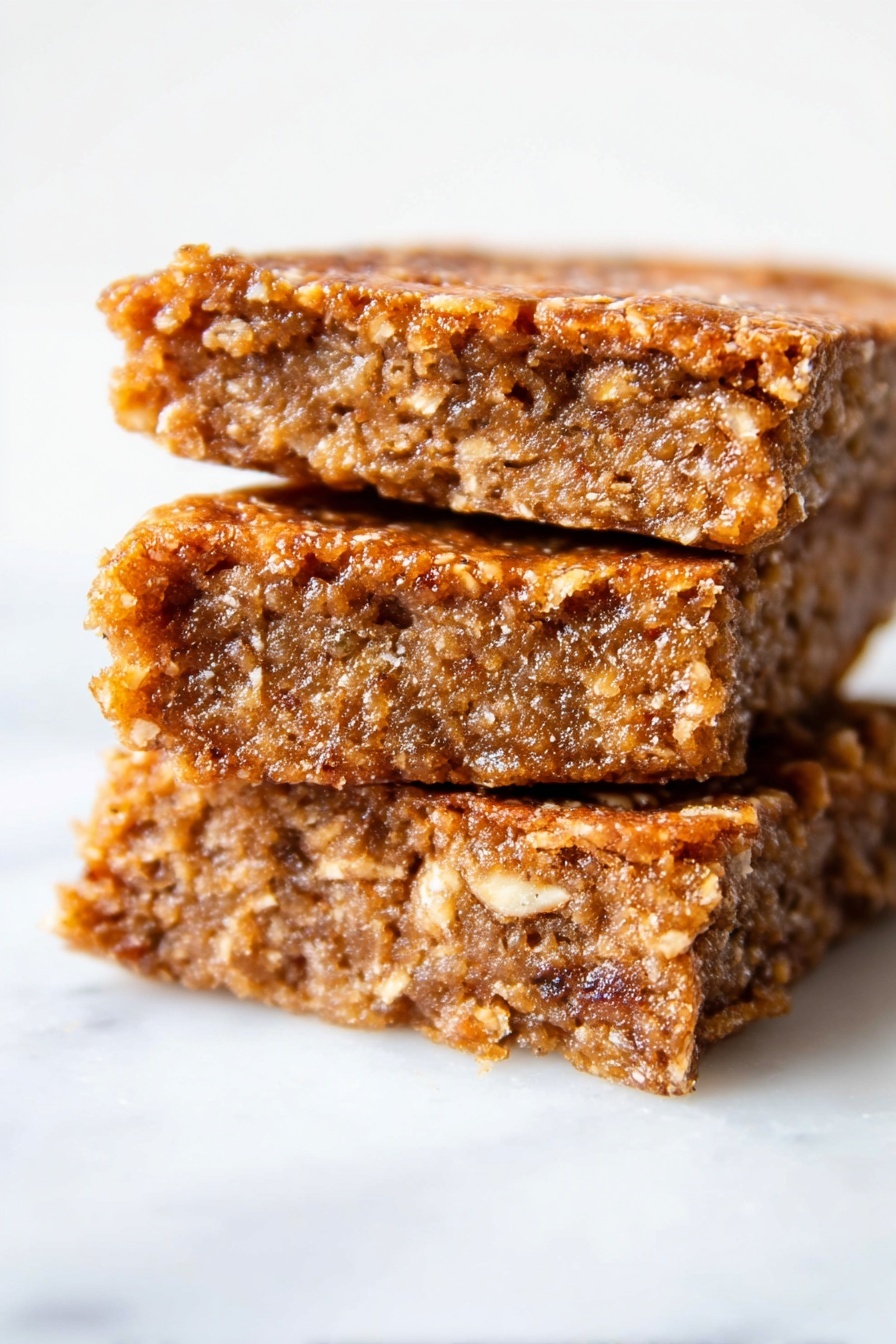 Healthy Apple Oatmeal Cake, Healthy Apple Oatmeal Cake, wholesome apple oatmeal cake, gluten-free apple oatmeal dessert, easy healthy cake - The image shows three brown, textured snack bars stacked on top of each other on a white marbled surface. Each bar looks soft and moist inside with a rough, slightly crispy outer layer. The bars have an uneven, crumbly texture with small visible bits that suggest oats or nuts, and their edges appear slightly jagged. The lighting highlights the bars’ warm color and their dense, chewy appearance. Photo taken with an iphone --ar 2:3 --v 7