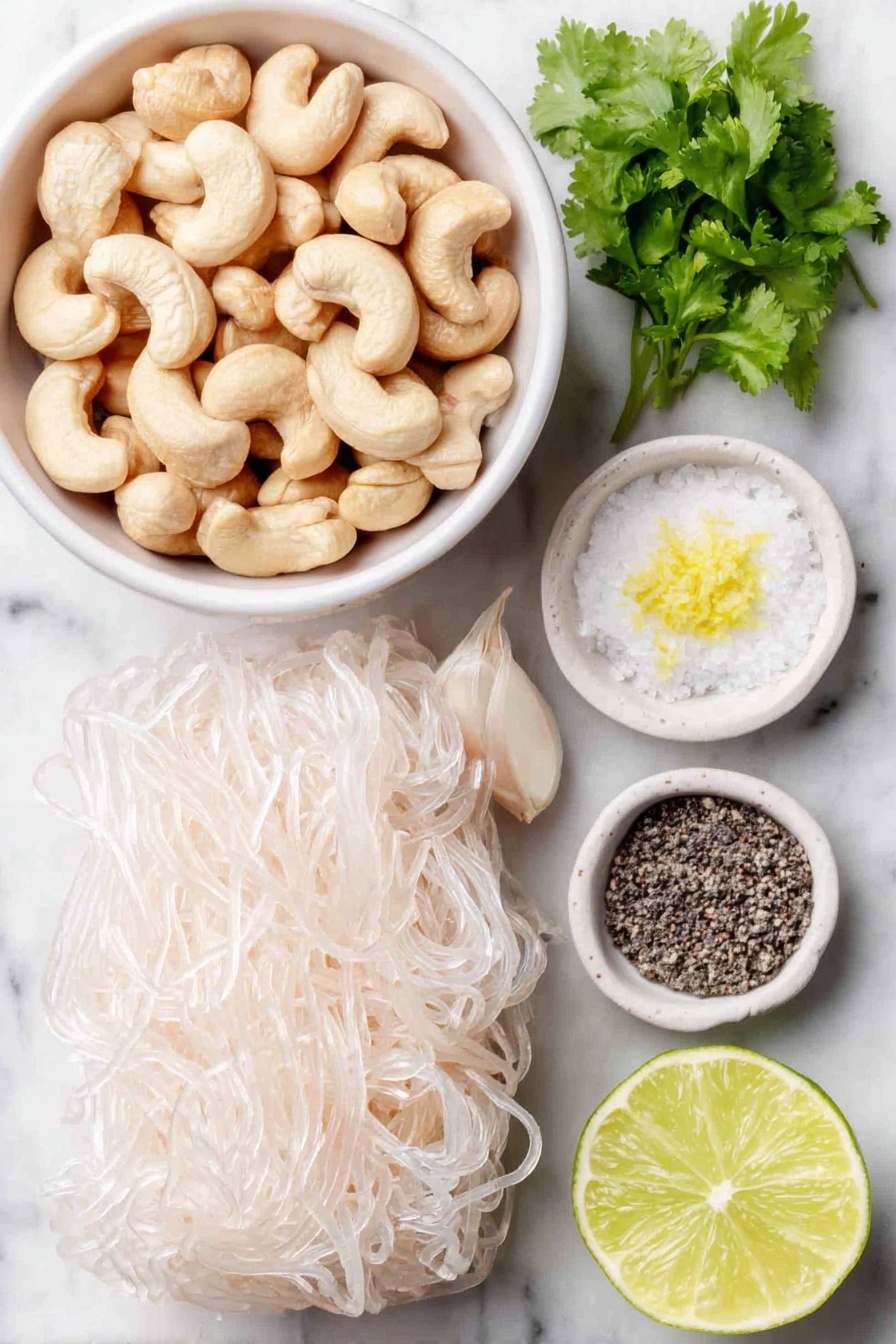 Vegan Cilantro Lime Noodles, vegan noodle recipes, healthy plant-based noodles, quick vegan dinners, cilantro lime pasta - Flat lay of raw cashews in a small pile, a small handful of bright green cilantro sprigs, two whole uncracked garlic cloves, a whole fresh lime with one half cut to show the juicy interior and scattered lime zest, a small white ceramic bowl filled with clear water, a small white ceramic bowl containing coarse salt, a small white ceramic bowl with cracked black peppercorns, and a neat bundle of tofu shirataki spaghetti shaped noodles, all arranged in perfect symmetry on a clean white marble surface, soft natural light, photo taken with an iPhone, professional food photography style, fresh ingredients, white ceramic bowls, no bottles, no duplicates, no utensils, no packaging --ar 2:3 --v 7 --p m7354615311229779997